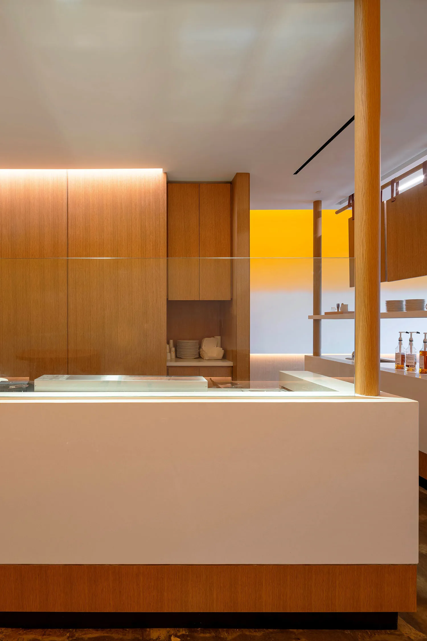 Empty kitchen with white walls, wooden cabinets, and a sink on the left side, with various bowls on the countertop