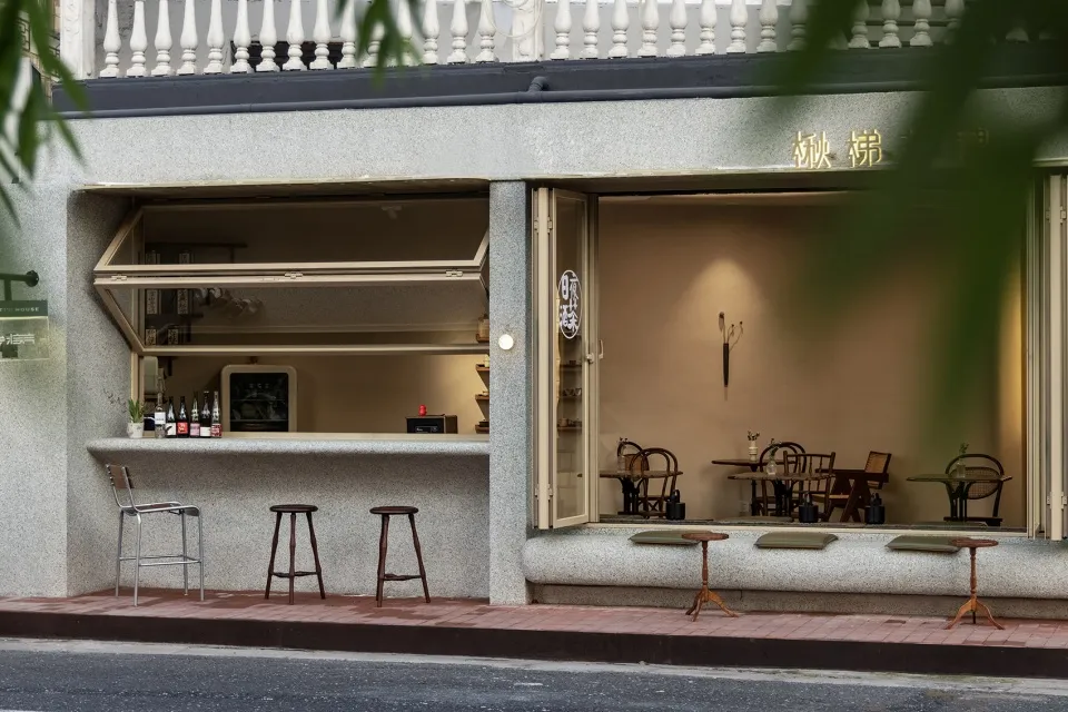 現代亞洲餐廳設有吧台與高腳椅、座椅及盆栽，採用灰白配色與溫暖燈光