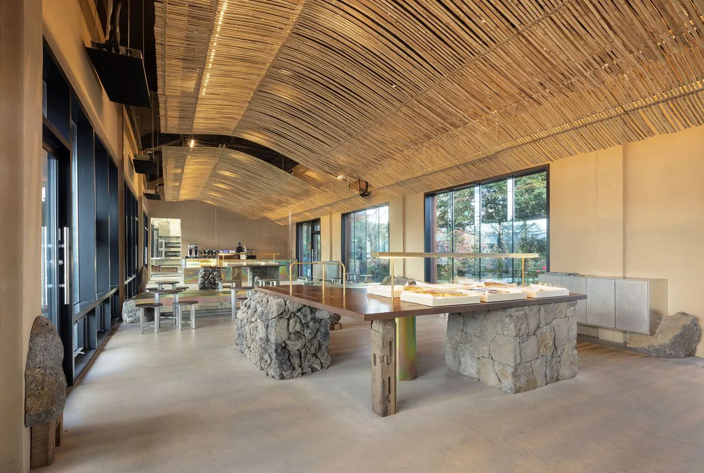 A modern dining space with a wooden table and metal chairs, surrounded by high ceilings and featuring two dining tables with comfortable seating and scattered cups