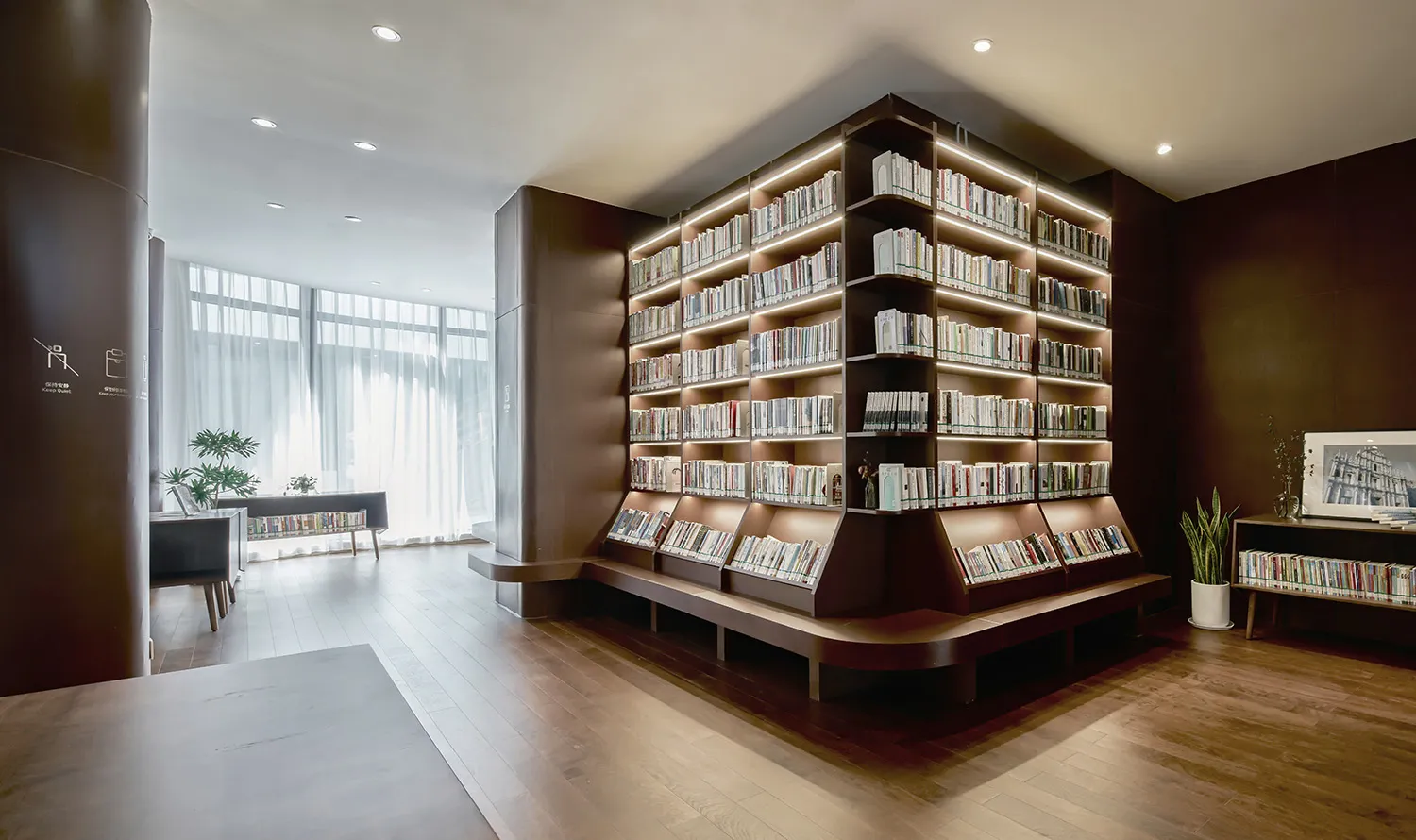 A well-lit library with numerous books on wooden shelves, arranged in an organized manner, creating a calm and studious atmosphere
