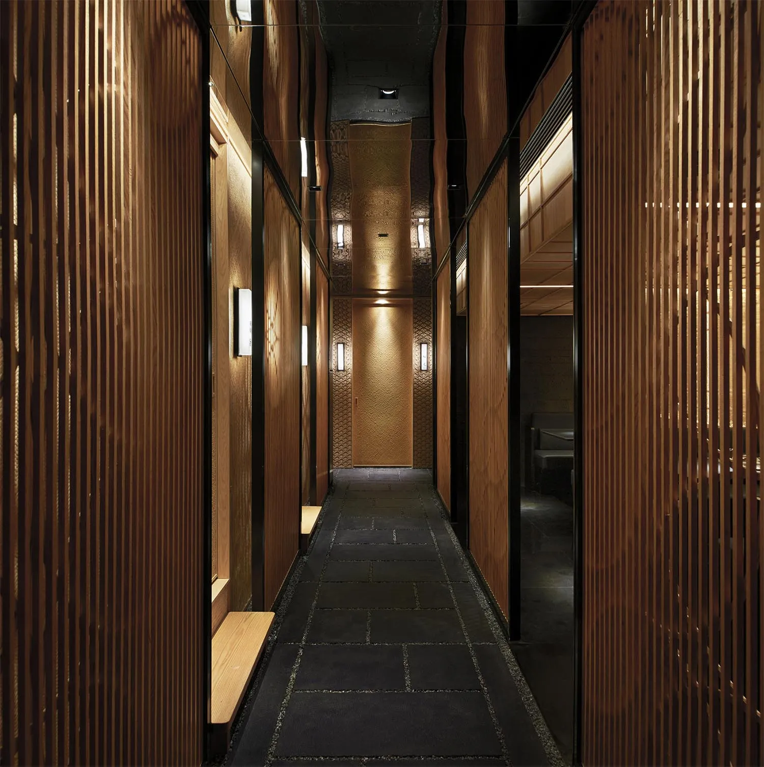 A modern hotel lobby with wooden walls and floors, featuring two benches and a functional design