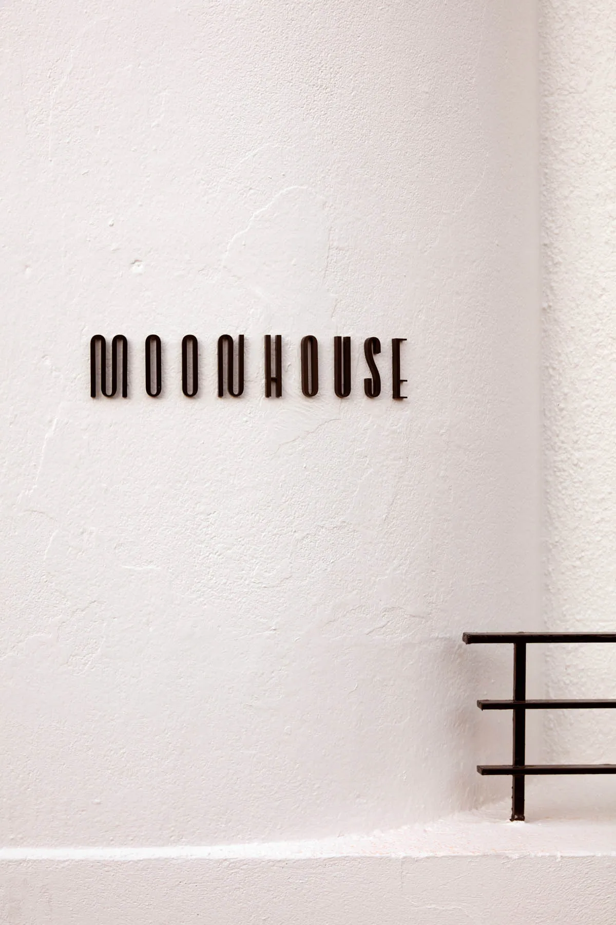 A white concrete building with a sign reading moonhouse, set against a blank background