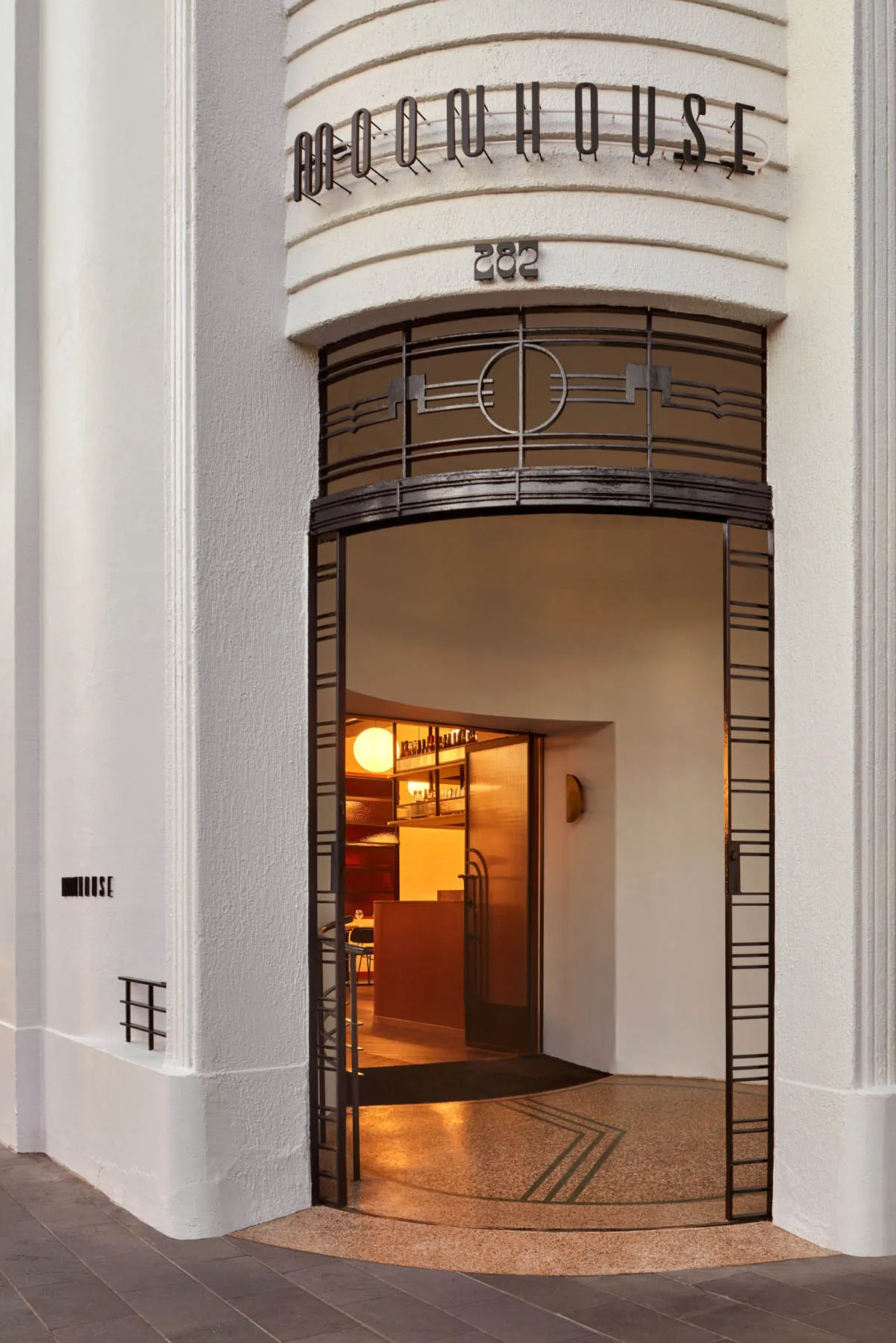A restaurant entrance with a glass doorway, comfortable seating, and a clean white color scheme