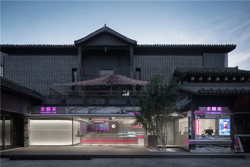 A black building with a red umbrella entrance, a balcony, and cozy interior with chairs, blending traditional and modern architectural styles