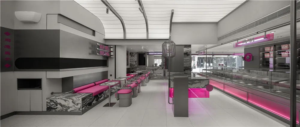 A modern restaurant interior with pink accents, artwork on the walls, and ample seating for guests