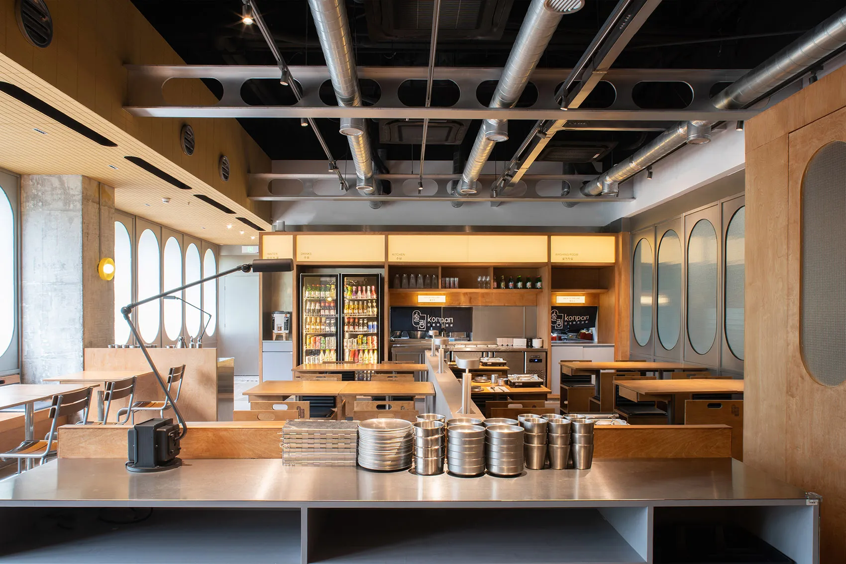 Industrial kitchen with a large dining table, chairs, and commercial appliances, with a focus on functionality and organization