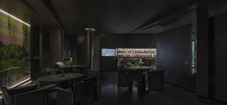 A sophisticated interior design showroom with a large black table surrounded by chairs and wine glasses, set against a neutral background