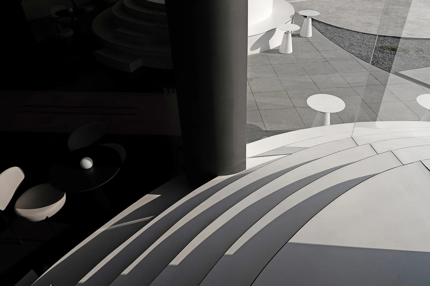 A modern building with a large pillar and several tables in a minimalist space with clean lines and simple design elements