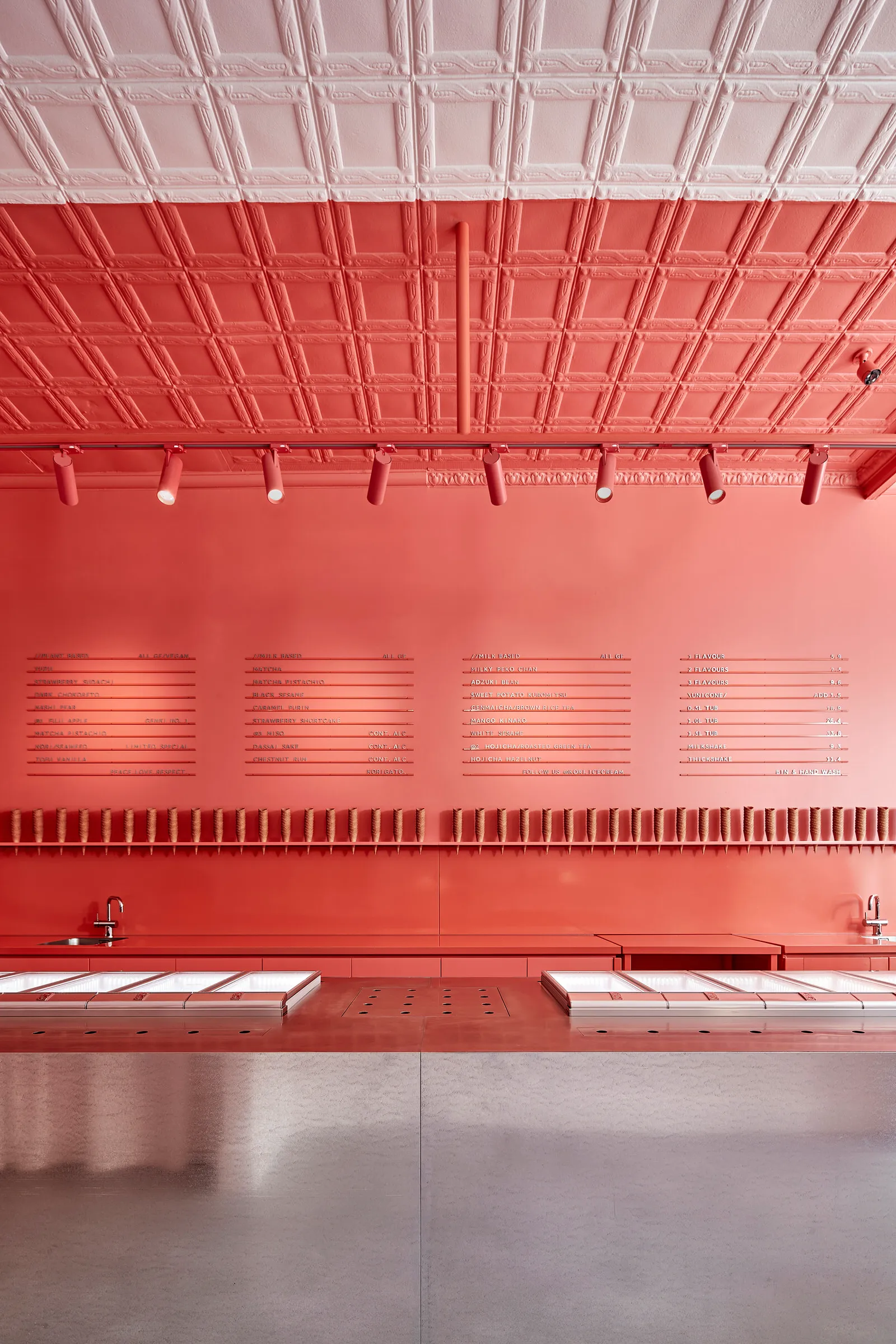 A modern restaurant interior with a red accent wall, counters, and signs, creating a warm and inviting atmosphere