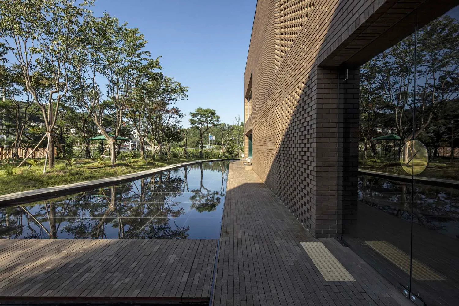 A serene outdoor space with a brick building, empty pool, and surrounding trees