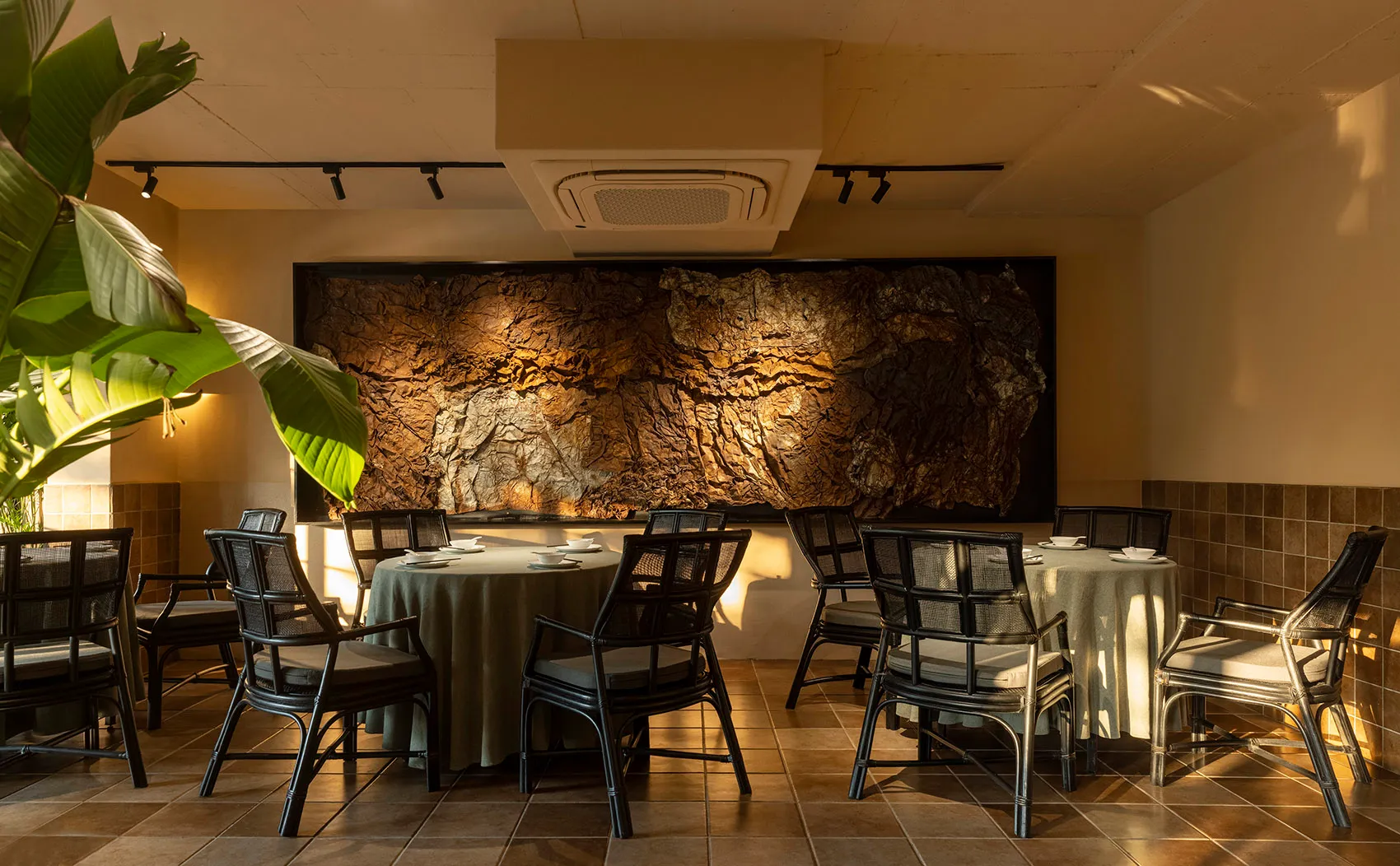 Dining area with a large wooden wall, tile floor, and multiple chairs around a table, creating a warm and inviting atmosphere