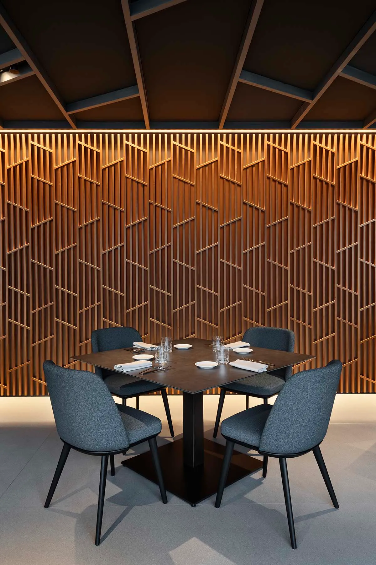 Cozy dining space with a wooden table and grey chairs, surrounded by cups and a warm atmosphere