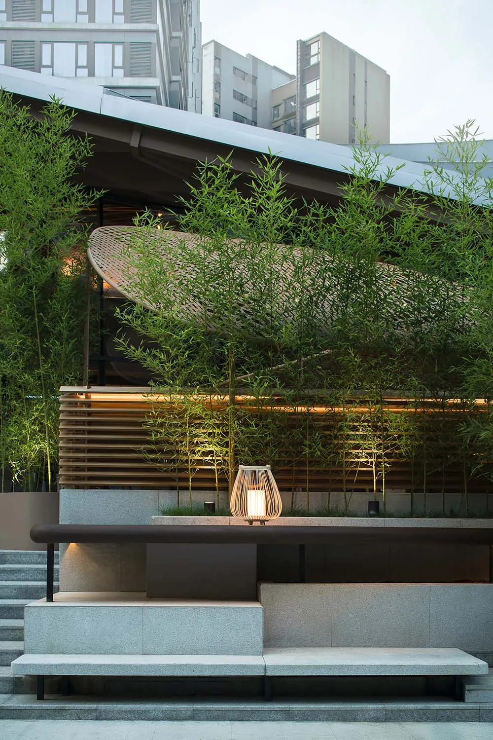 A modern building with a wooden table and surrounding potted plants, conveying a sense of tranquility and harmony between indoor and outdoor spaces