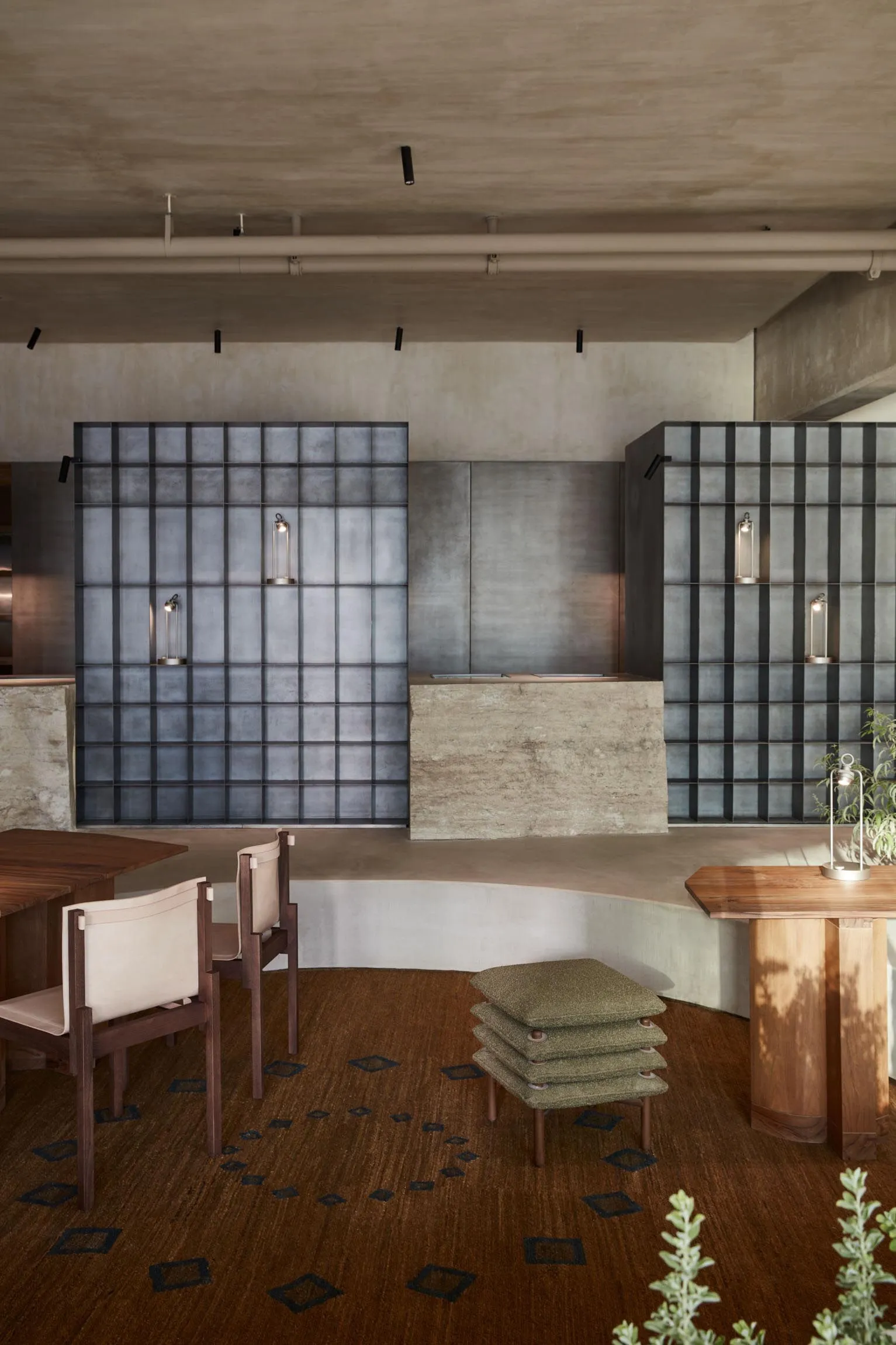 Modern interior design showroom with a concrete wall, wooden floors, two chairs, and a dining table, giving a clean and inviting atmosphere