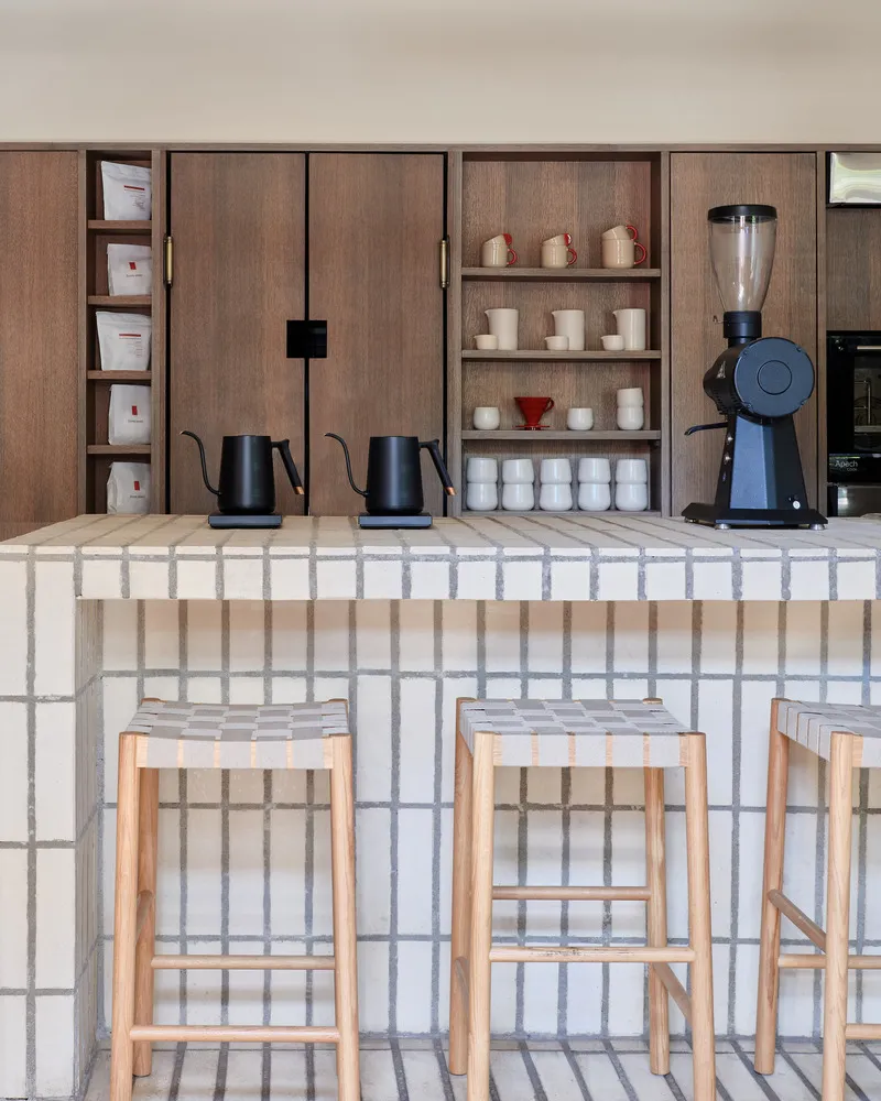 Interior design showroom with a counter, stools, cups, bowls, and bottles, designed for displaying kitchenware