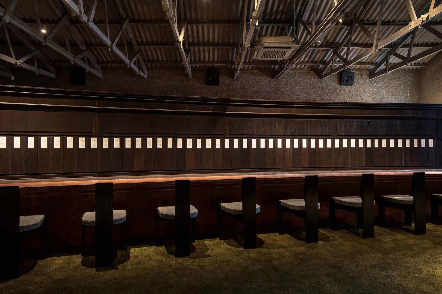 Cozy indoor bar area with wooden walls and tables, featuring a dining table and chairs, creating a warm and inviting atmosphere for socializing and enjoying drinks