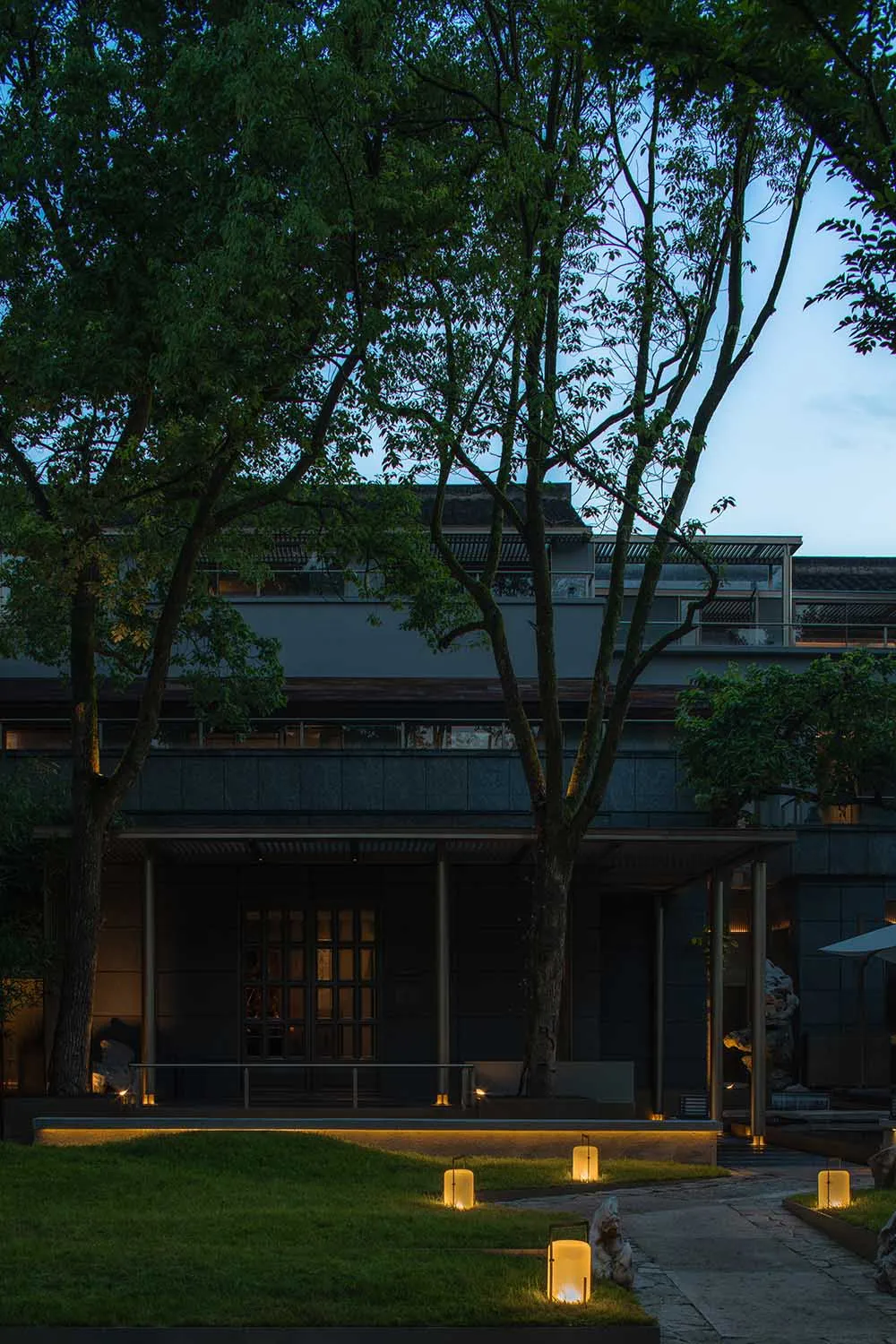 現代室內空間融合灰白元素，包含客廳區與帶椅餐廳區，並透過窗外樹木連結自然