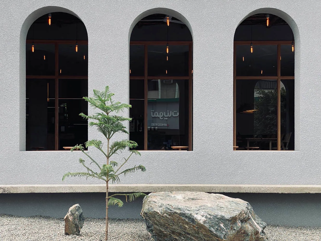 Modern building with a concrete facade, large windows, and two trees in front