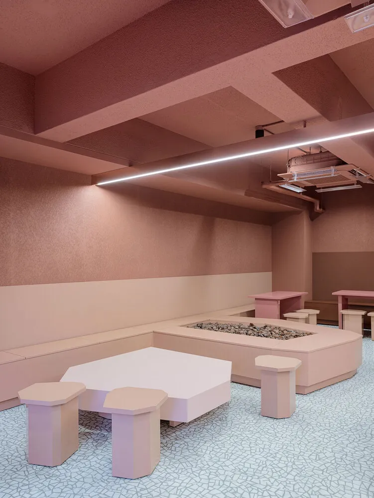 A warm and inviting cafe with pink walls, white tables, and multiple dining areas with chairs, creating a comfortable and relaxing atmosphere