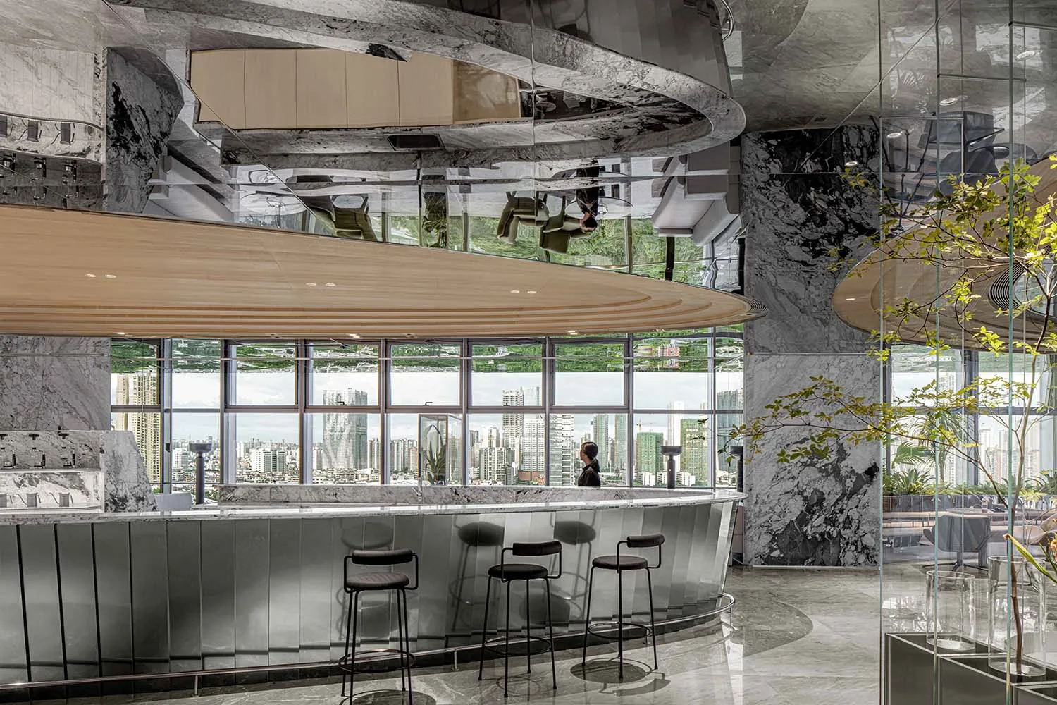 A modern bar area with a curved marble counter, stools, chairs, and tables, creating a sophisticated and inviting atmosphere