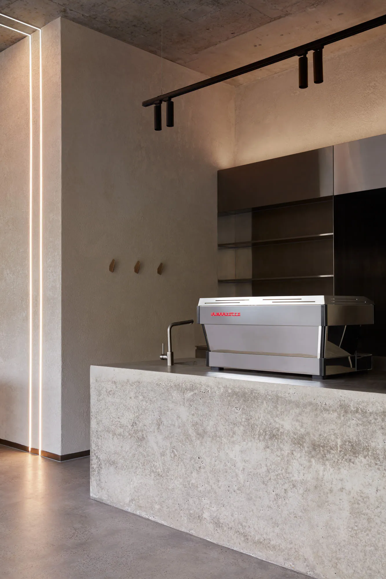 Modern industrial kitchen with a silver coffee maker on a concrete countertop and floor