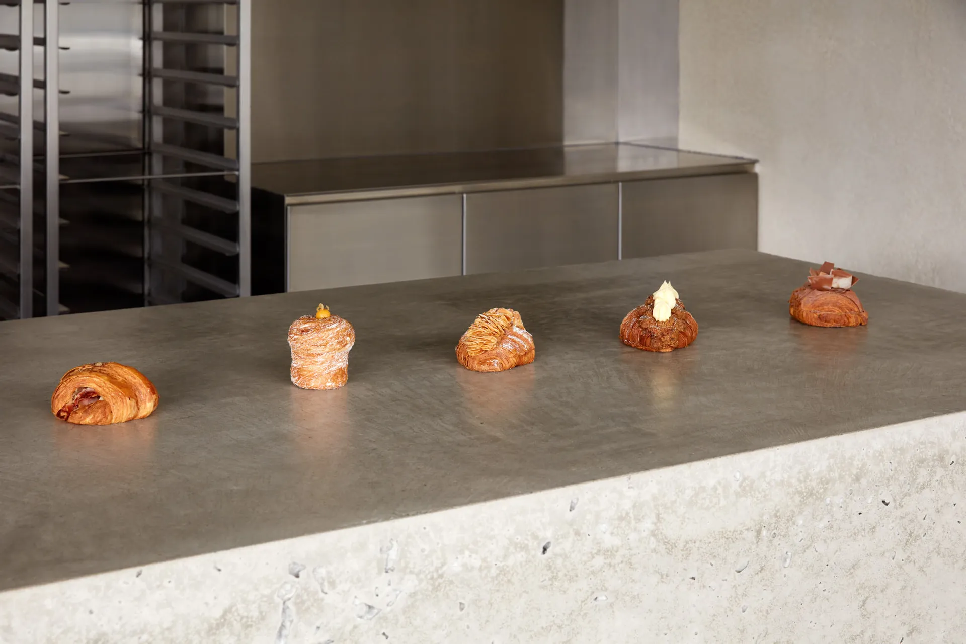 A modern kitchen countertop with four pastries arranged neatly, set against a concrete surface with a sleek appearance