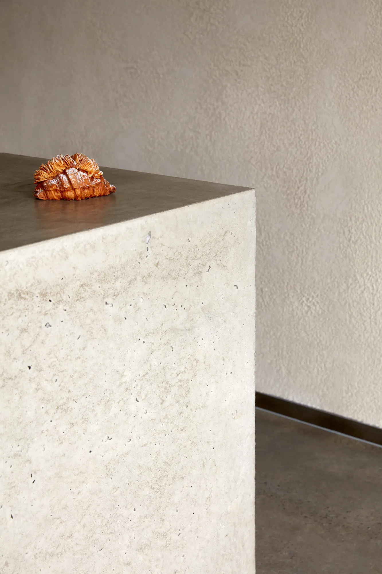 A real photo of a concrete wall with a small piece of food on top, giving a modern and industrial feel