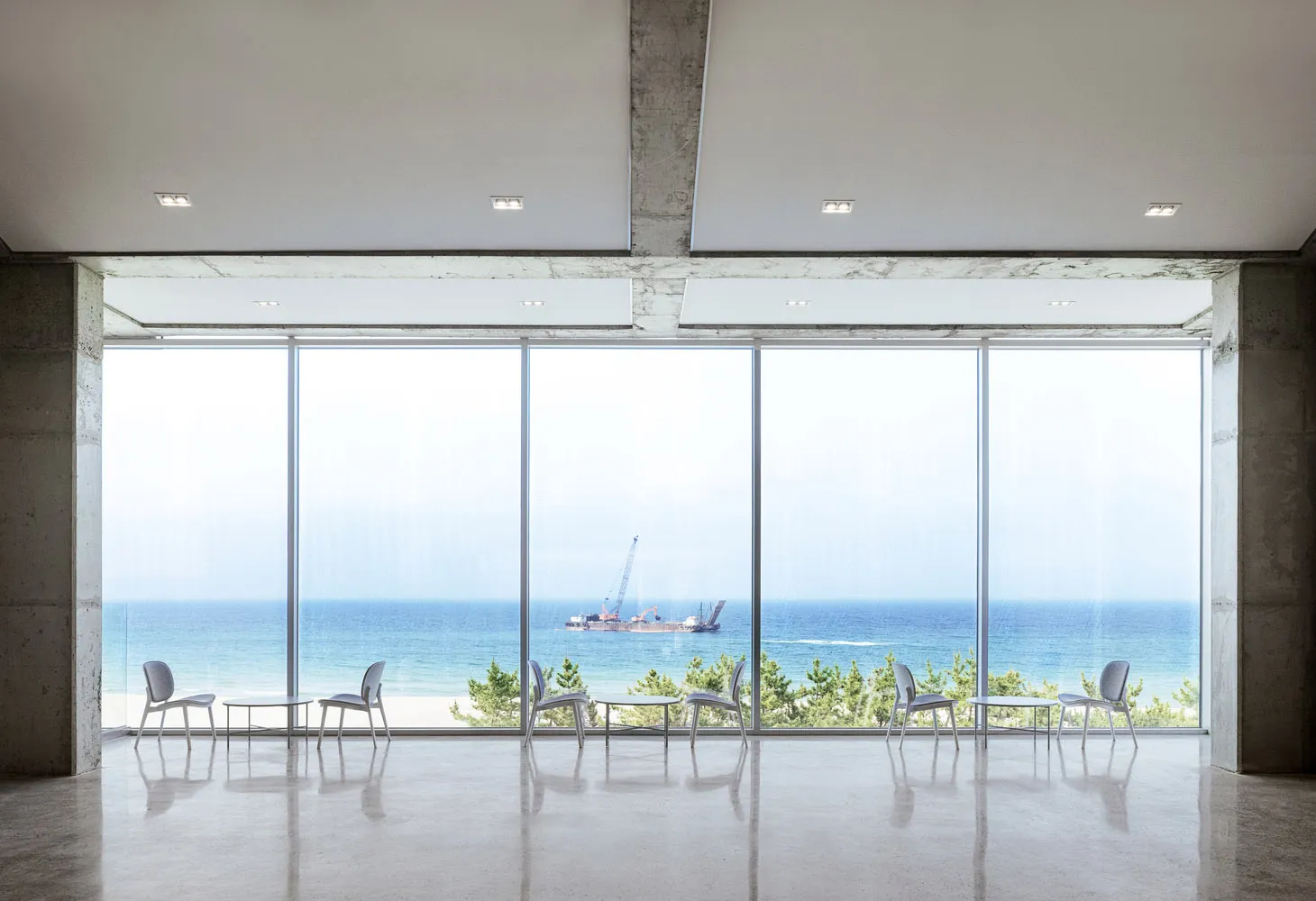 Open coastal living space with large windows, chairs, and a serene atmosphere