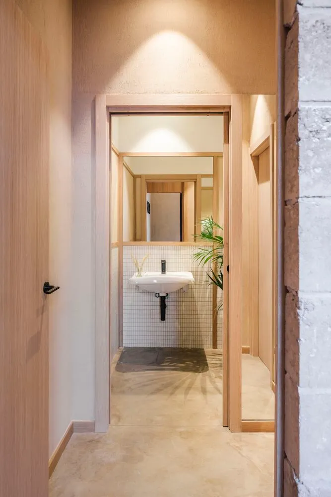 Bathroom with two sinks, wooden walls, and a tiled floor, lit by natural light