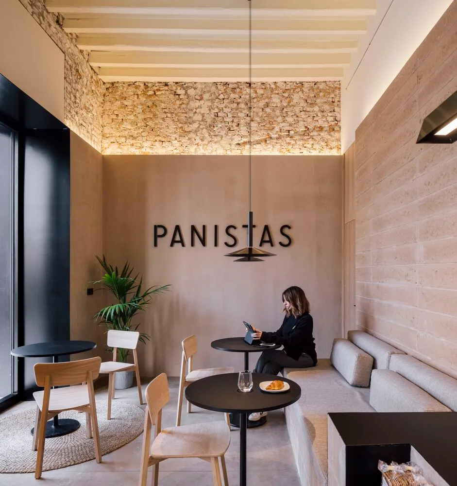 Cozy dining space with multiple tables, chairs, and potted plants, well-lit for a pleasant ambiance