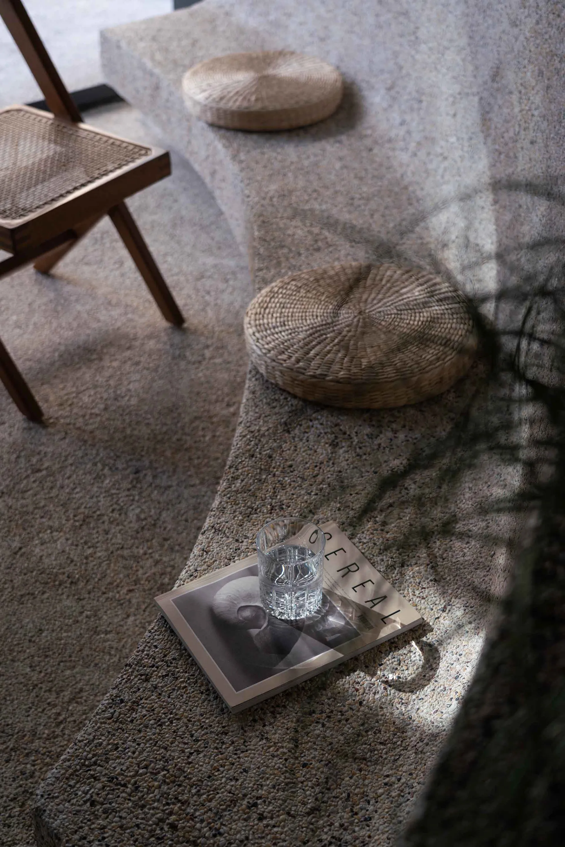 Cozy living area with a rugged floor, two chairs, a book, a cup, and a potted plant