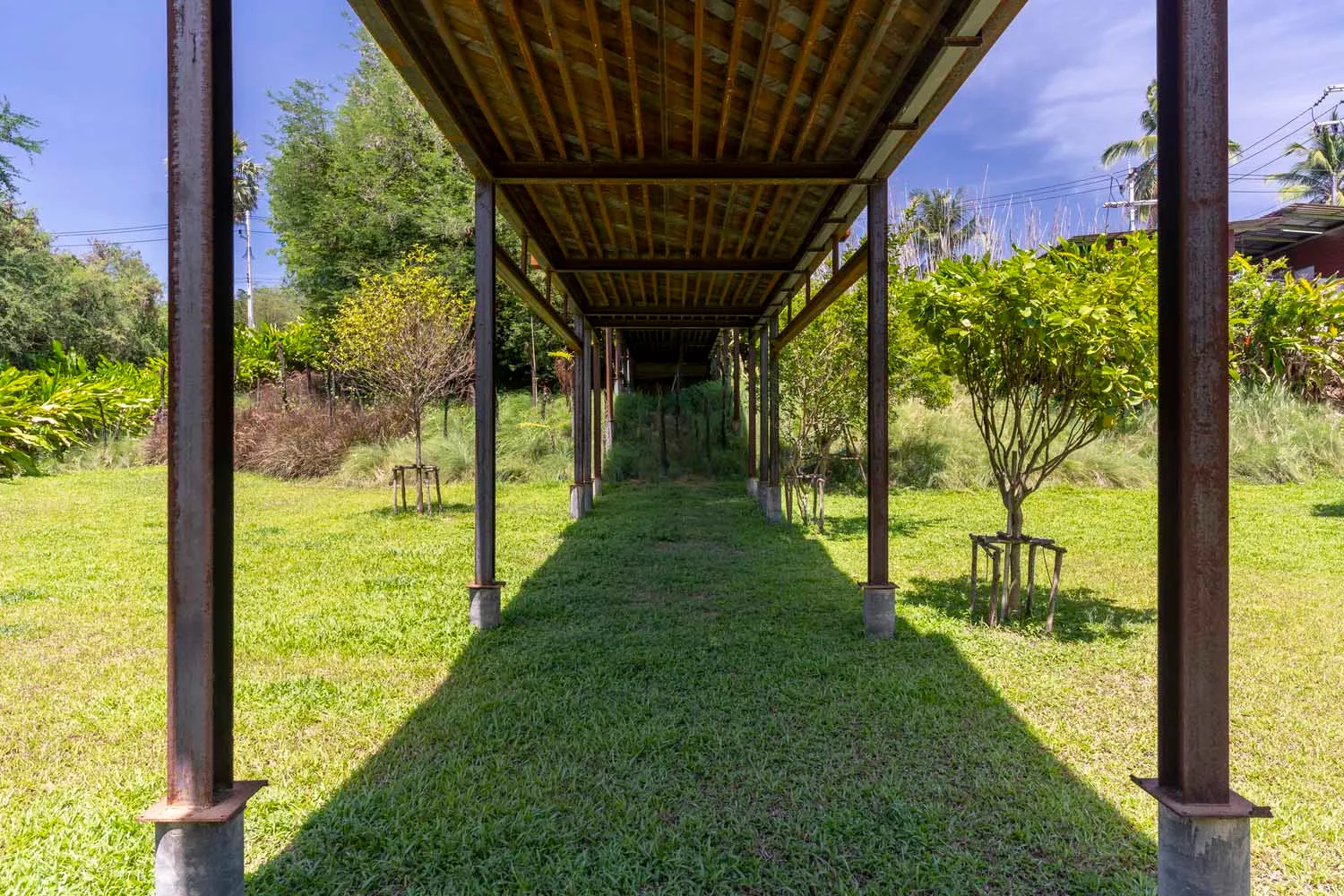 A wooden pavilion with a distinctive design features several benches for seating in a relaxing outdoor environment
