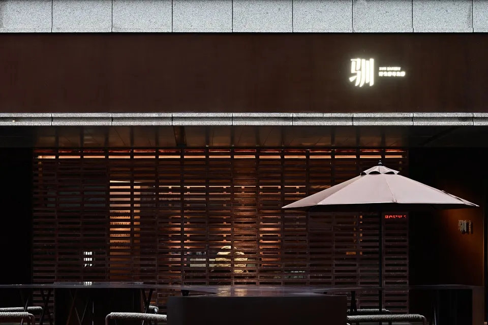 Cozy Asian restaurant with wooden walls and tables, comfortable seating, and an umbrella providing shade
