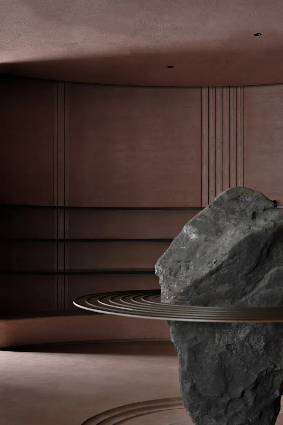 A modern living area with a brown color scheme and a large rock placed on a circular surface in the center of the room