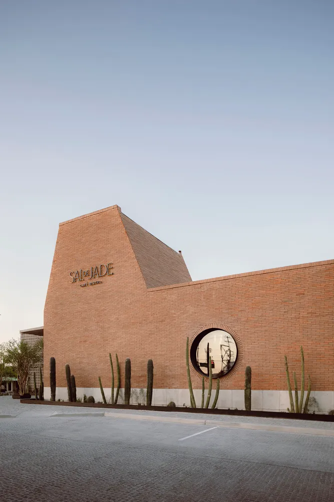 A modern house with a brick wall and cacti, featuring a round window and a warm, inviting atmosphere
