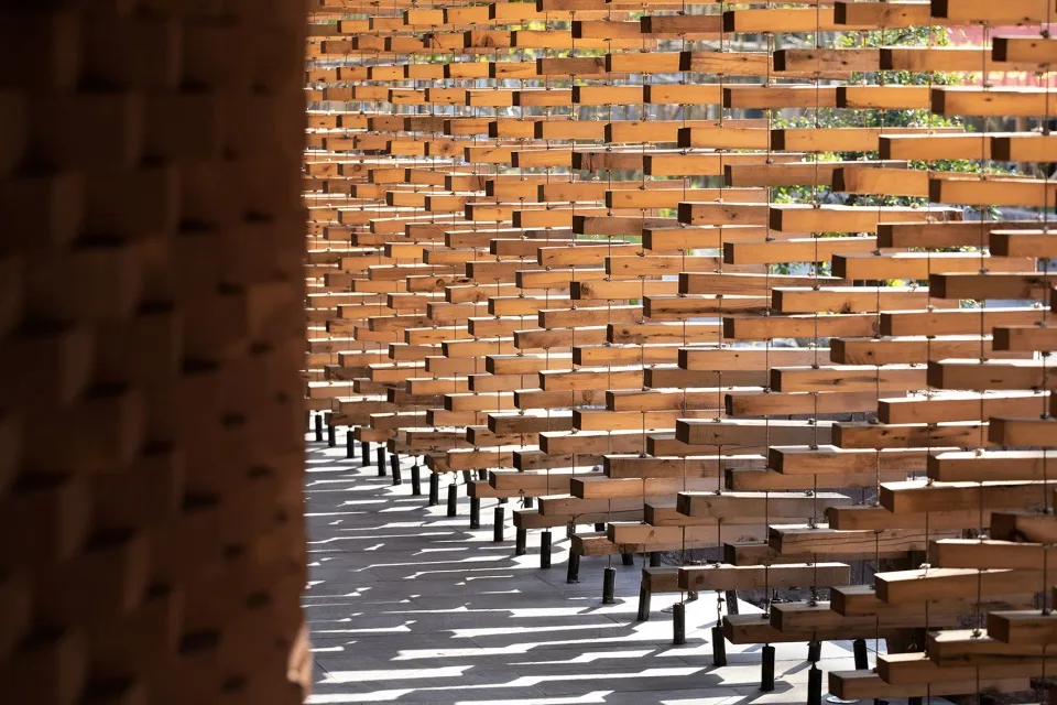 A calm and organized space with wooden benches arranged in rows on a concrete surface