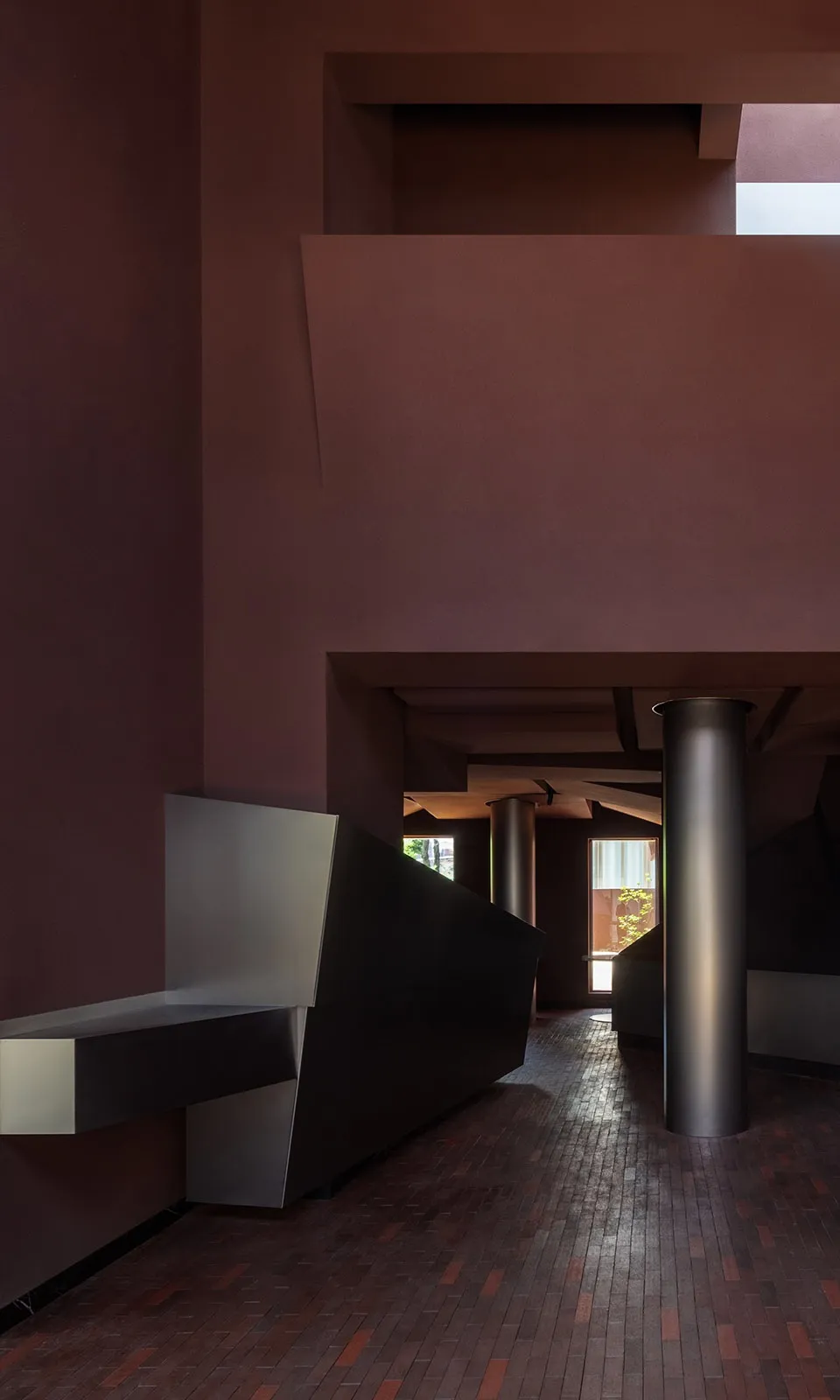 Modern minimalist space with a pink accent wall, black metal pole, and sleek furniture