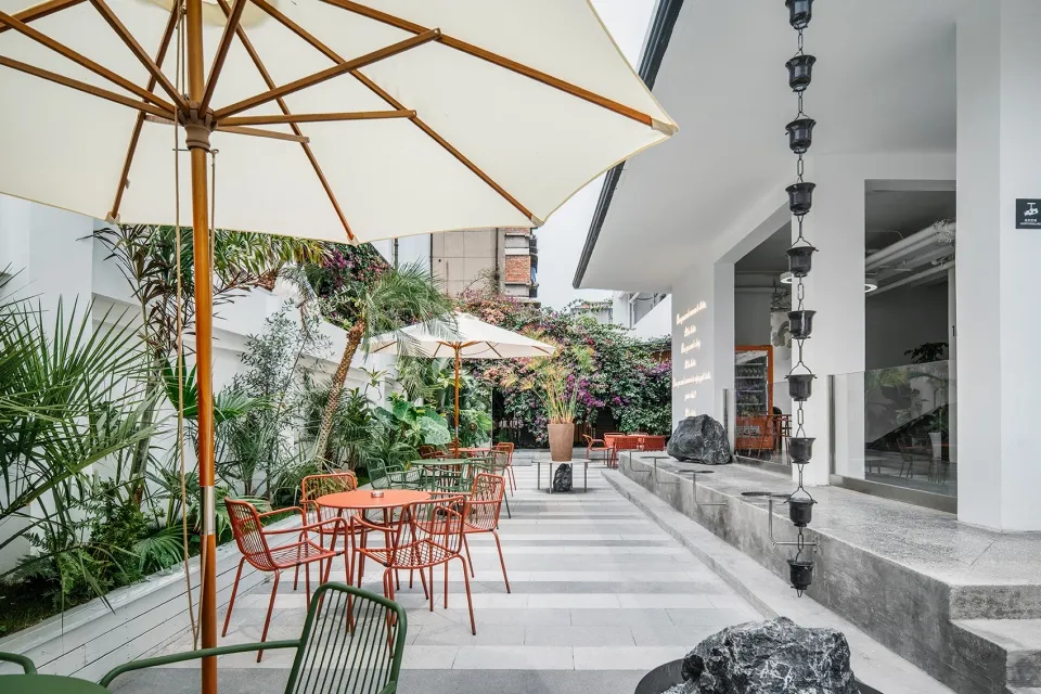 An inviting outdoor patio area with tables, chairs, umbrellas, and potted plants