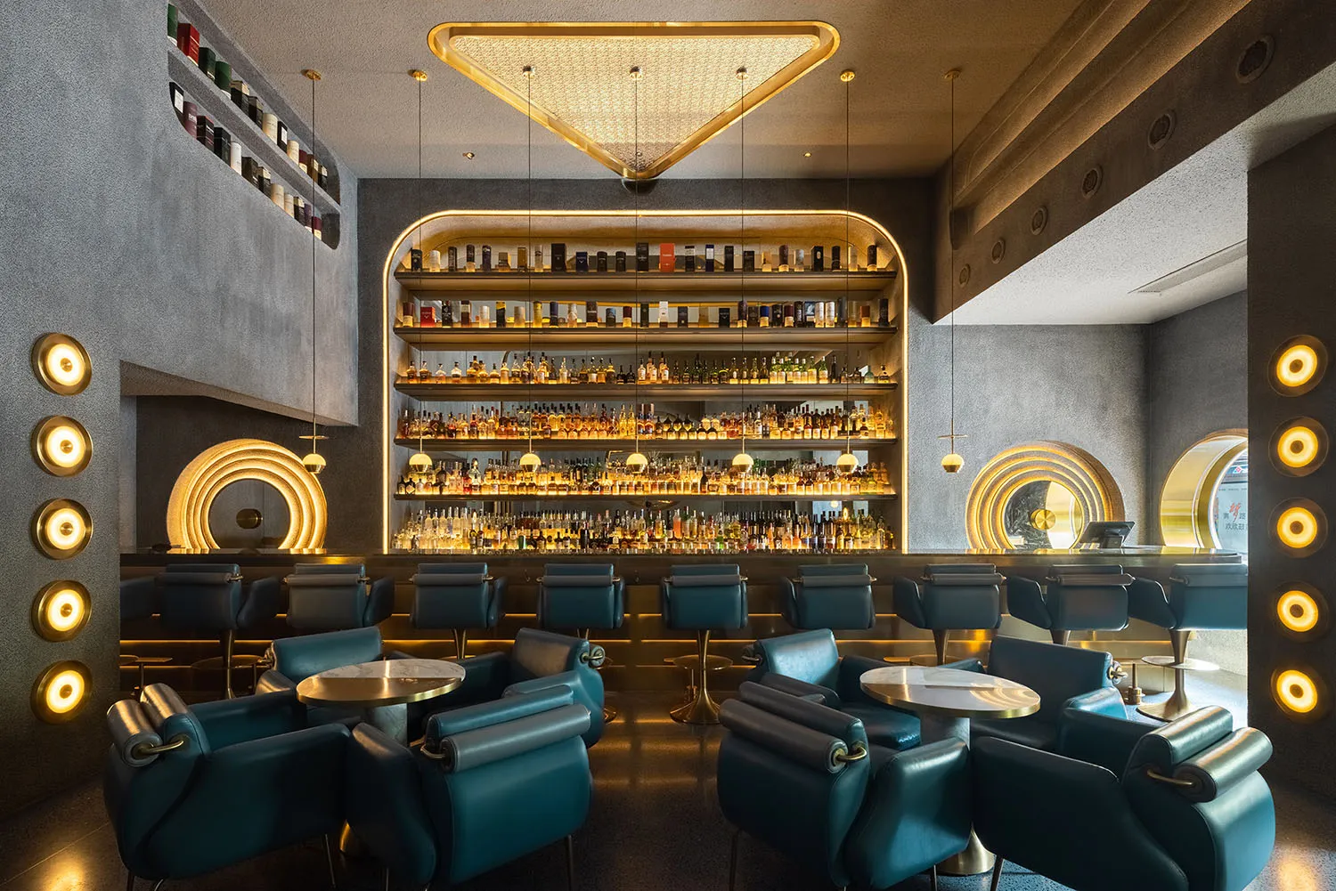A sophisticated bar area with a liquor display behind the counter, surrounded by chairs and an elegant atmosphere