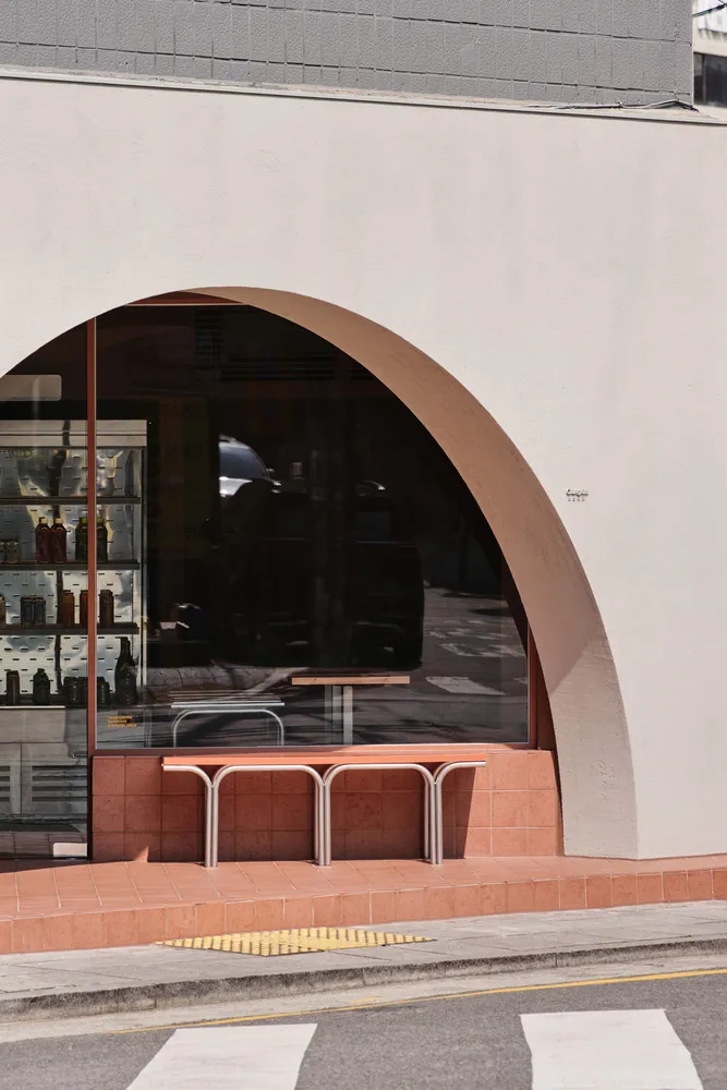 A modern restaurant interior with two dining tables, a bench, and white walls, creating a clean and inviting atmosphere