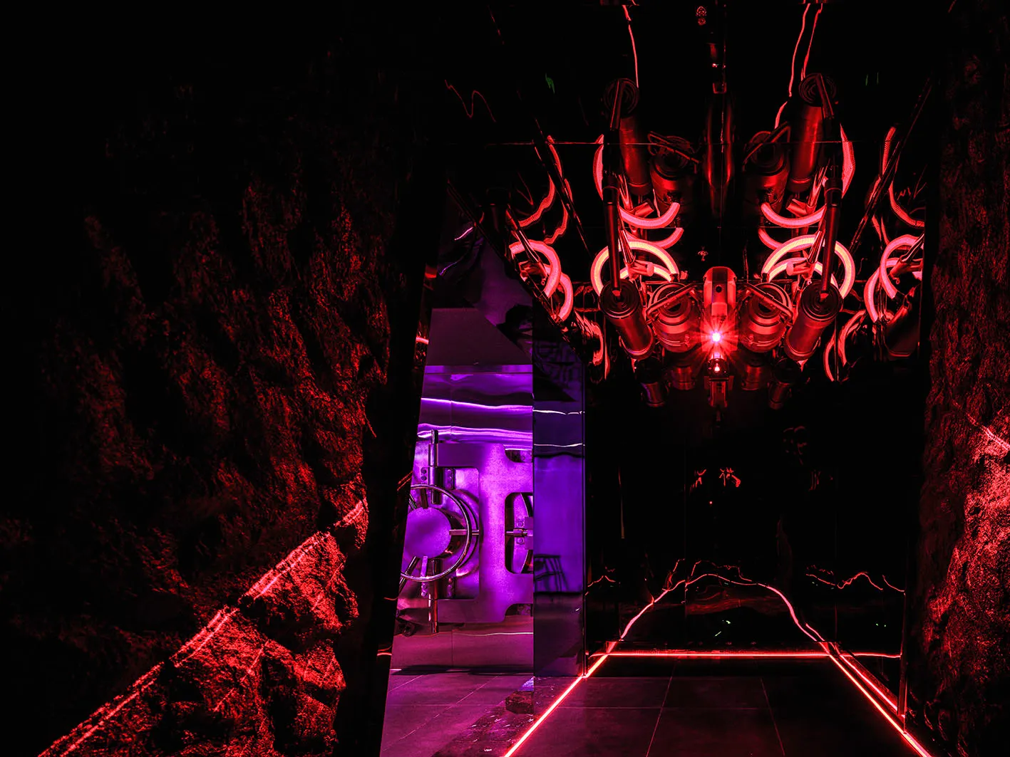 Industrial space with a large metal machine and red glow, surrounded by chairs and a high-tech atmosphere