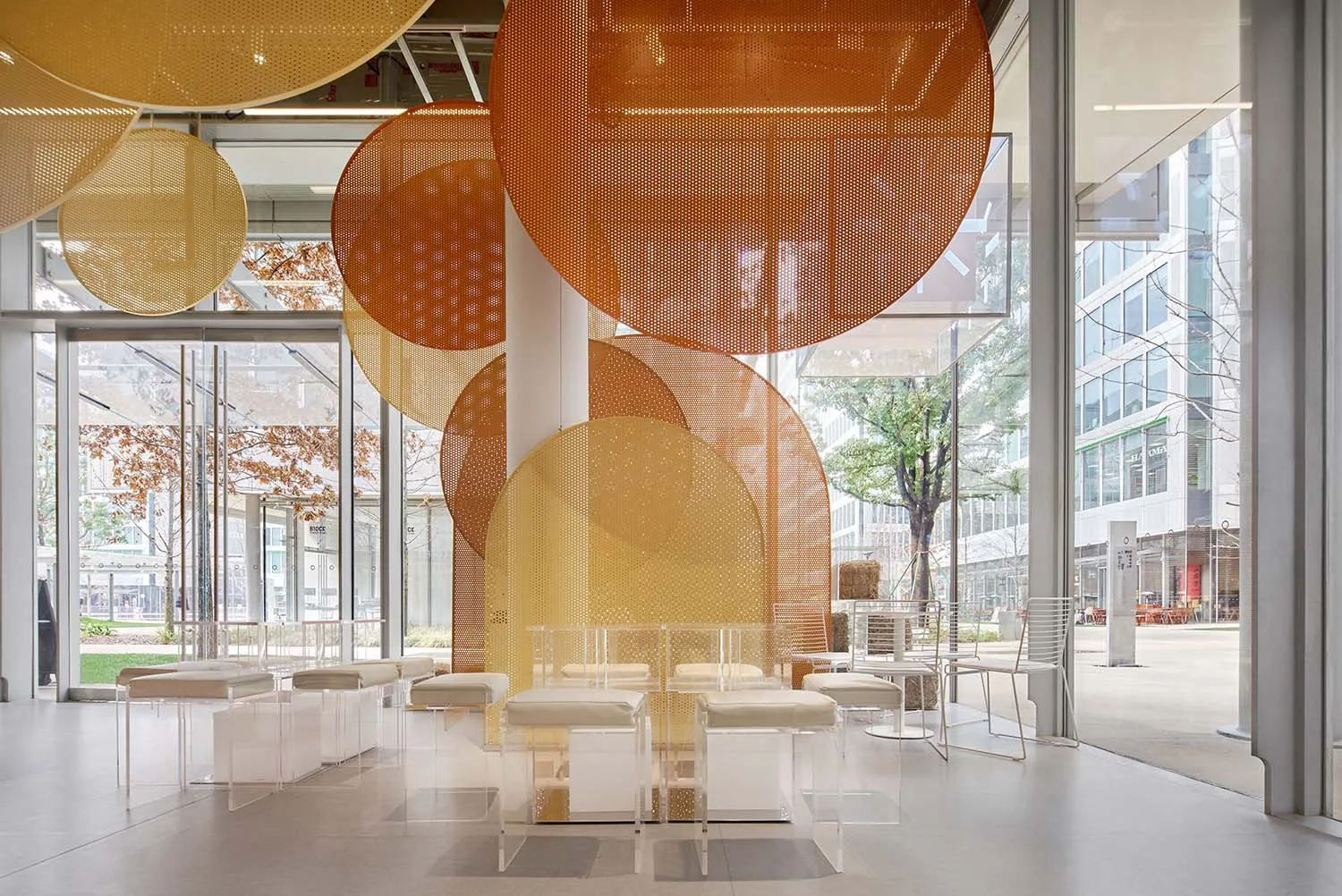 A bright and inviting indoor space with multiple white chairs and tables arranged for socializing and dining, with natural light coming through windows