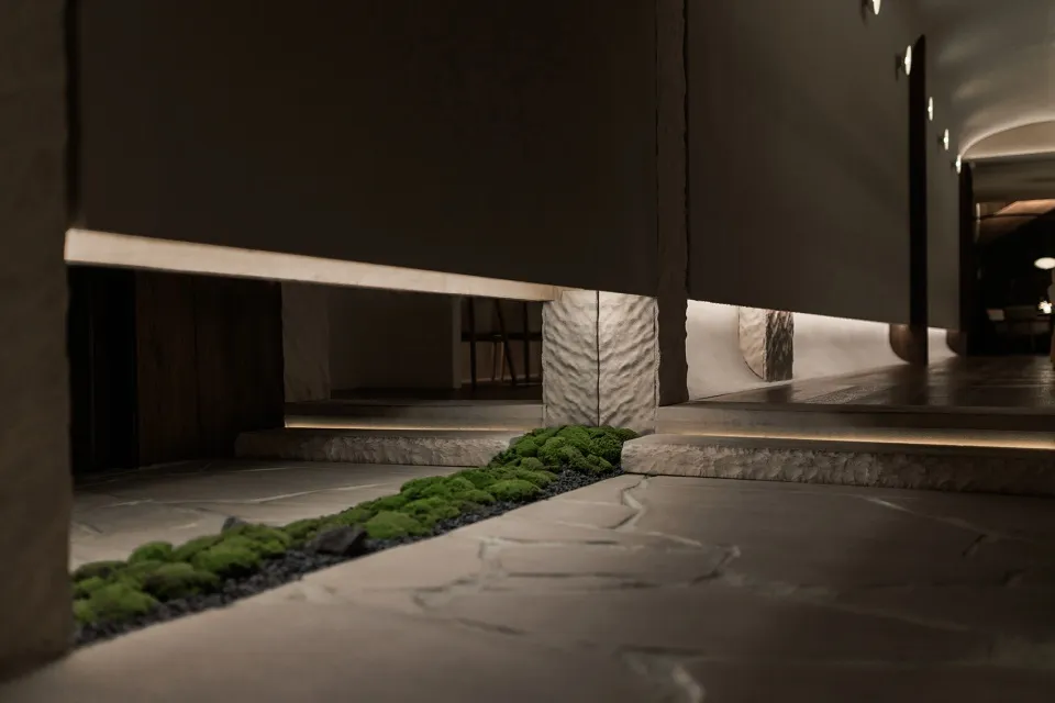 A calm indoor space with a stone wall, a small green plant, and two chairs, creating a serene atmosphere