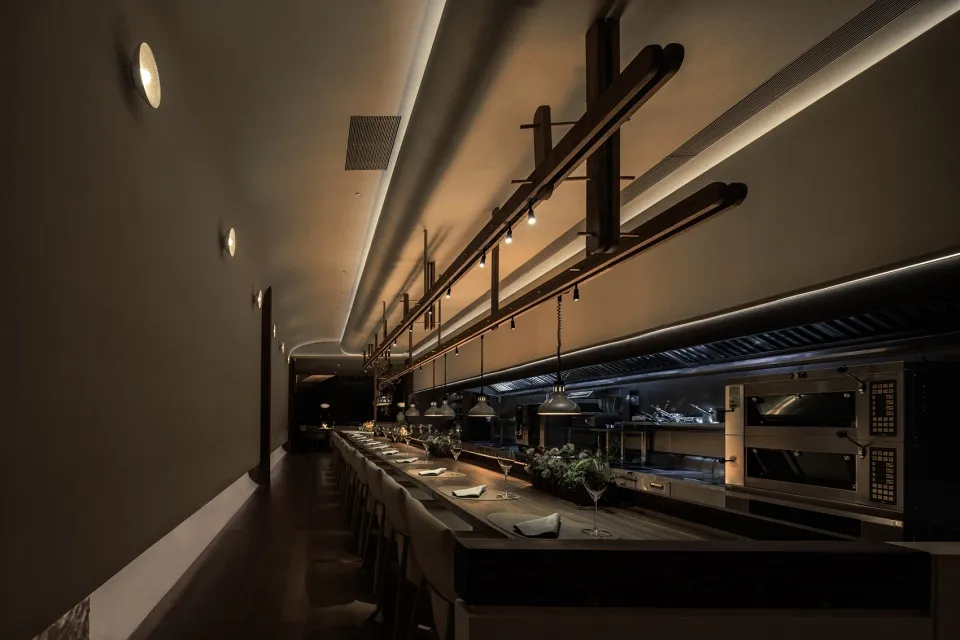夜晚寧靜溫馨的餐廳用餐區，配有長桌、椅子與盆栽