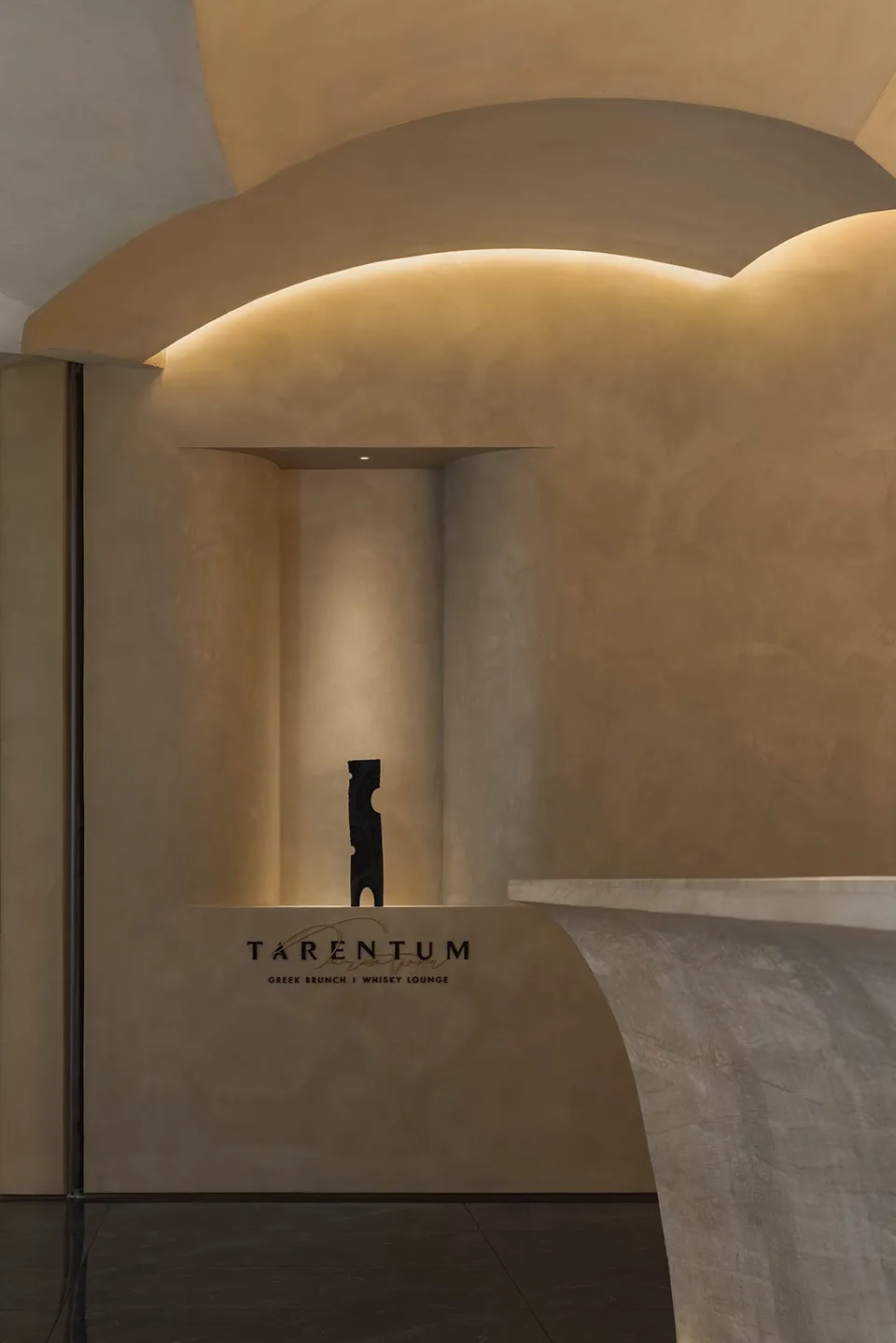 A modern art gallery with a black sculpture on a pedestal surrounded by artwork-adorned walls