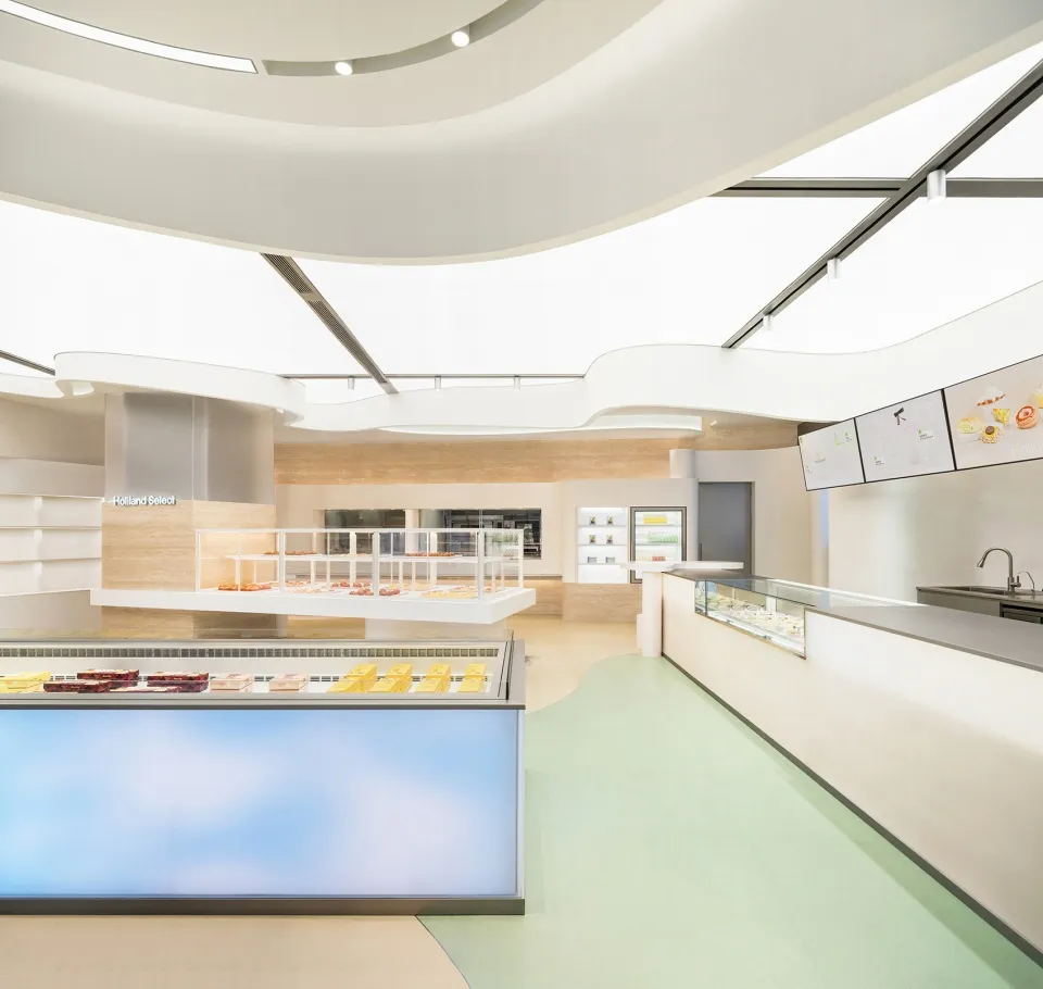 A clean and well-organized interior with a large glass display case filled with donuts and sandwiches, surrounded by a modern space