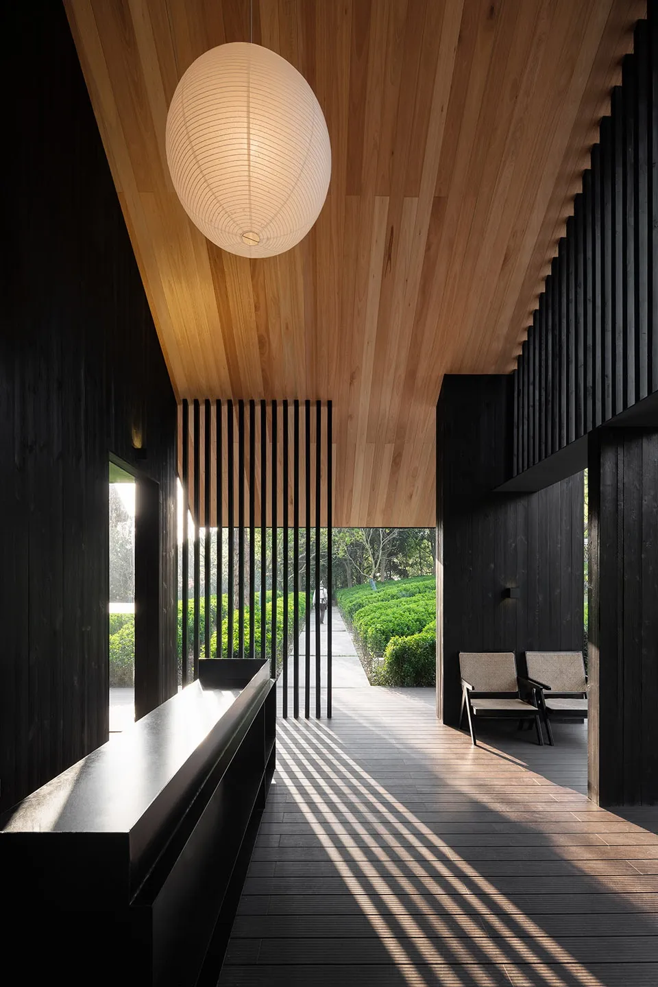 Modern living space with a black interior design theme, wooden floors and walls, and a dining table and couch