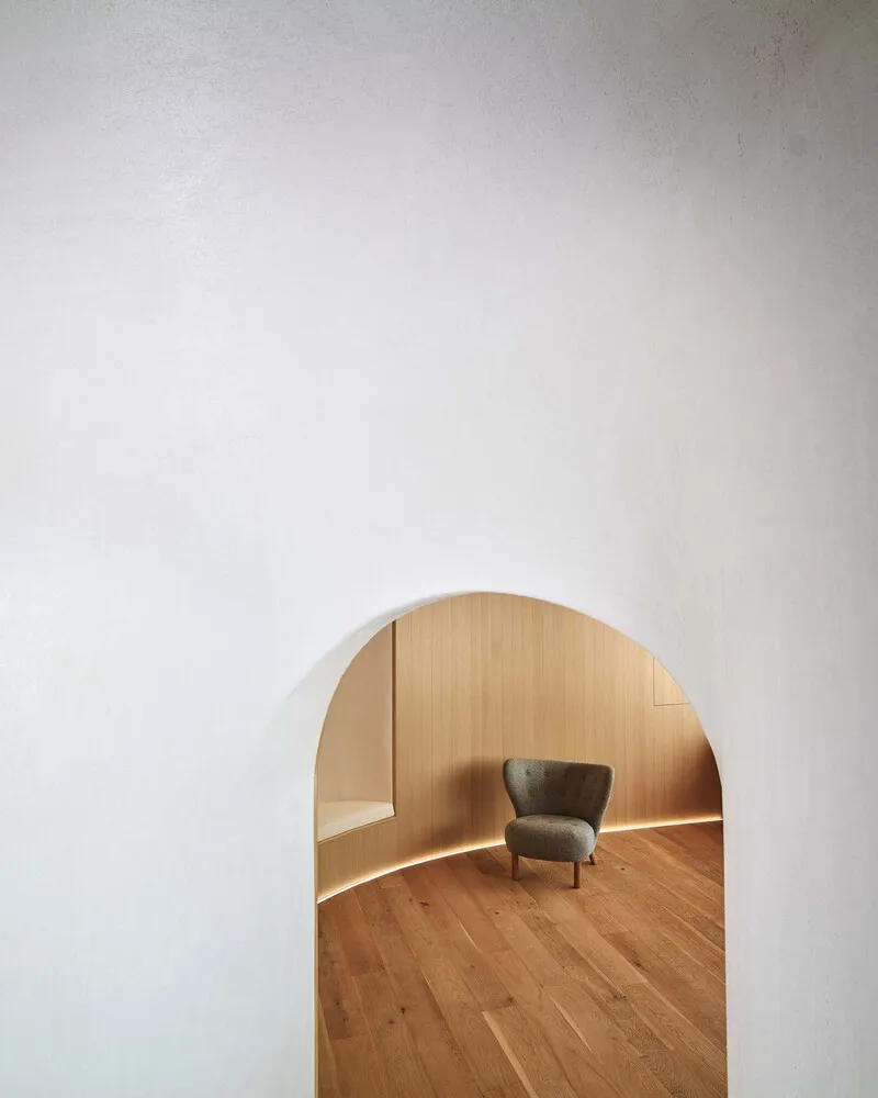 A minimalist interior design featuring a white room with wooden floors and a wooden chair, emphasizing simplicity and functionality