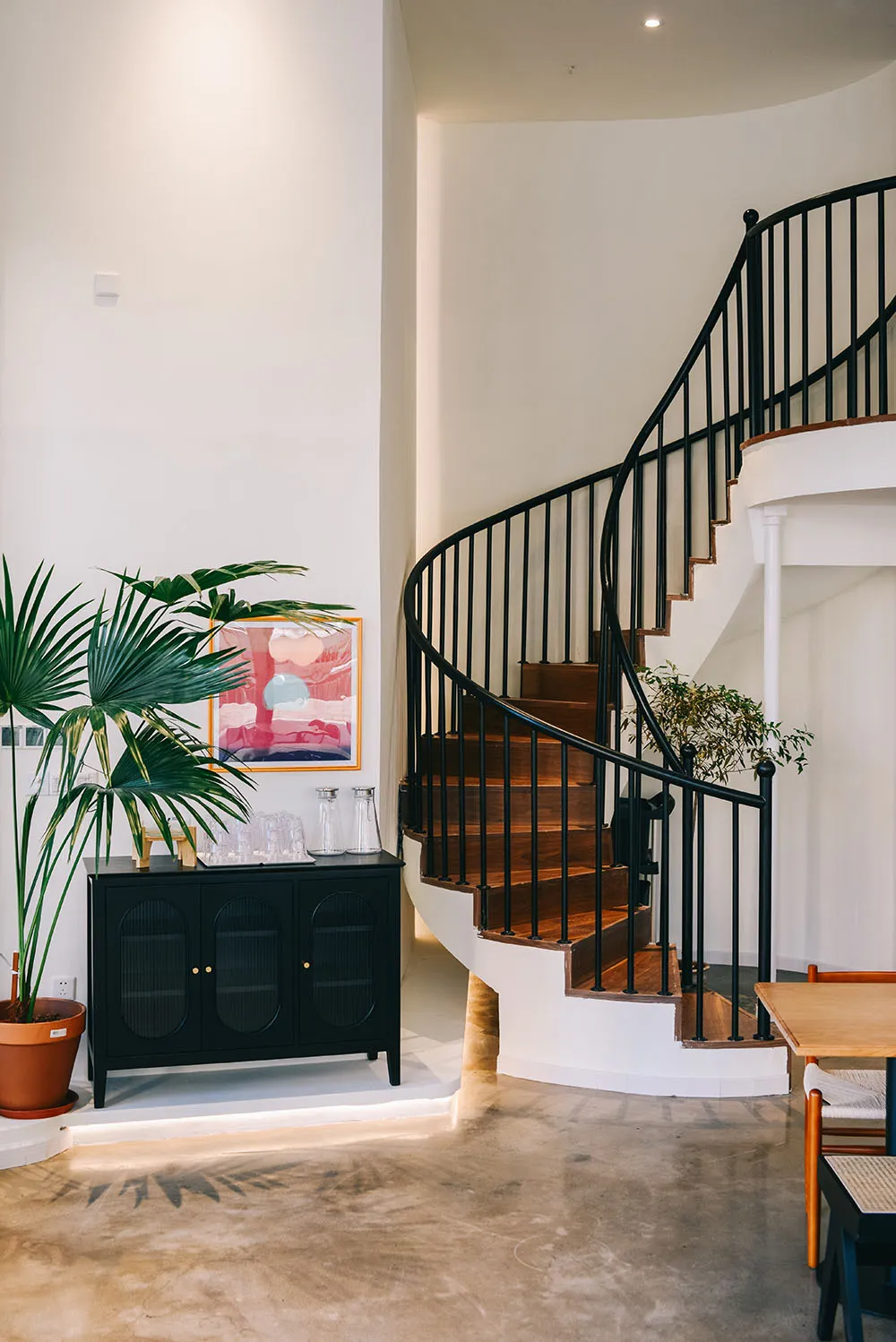 Interior staircase with wooden steps, two potted plants, and three vases, set against a neutral background
