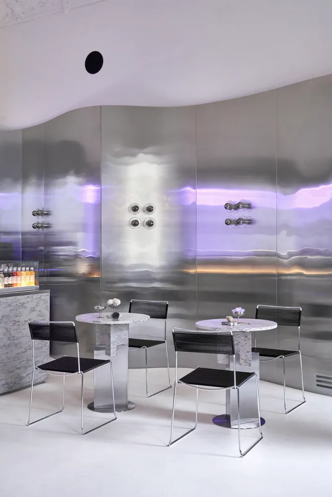 Modern bar area with a large mirror, tables, and chairs, providing ample seating and a stylish atmosphere